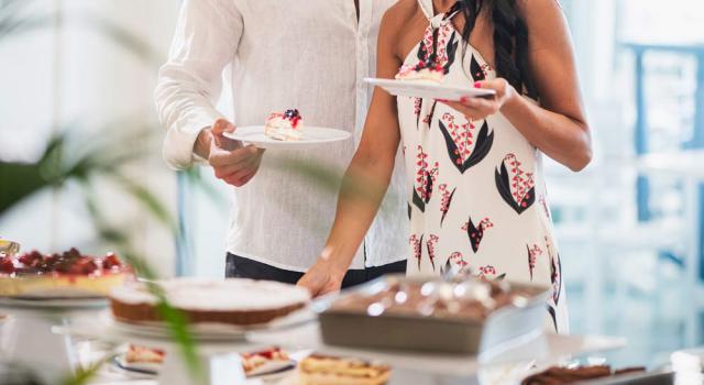 Two people select delicious desserts from a buffet, elegant and inviting atmosphere.