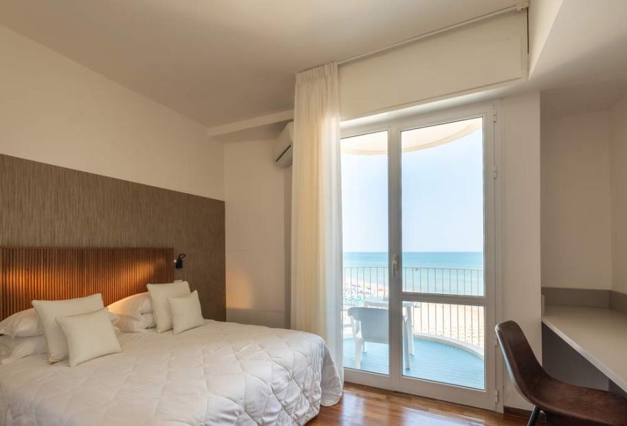 Bright room with sea view, cozy bed, relaxing atmosphere.