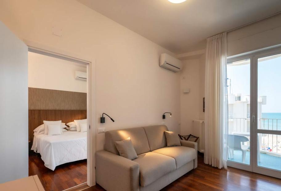 Bright room with sea view, cozy sofa, and inviting bed.