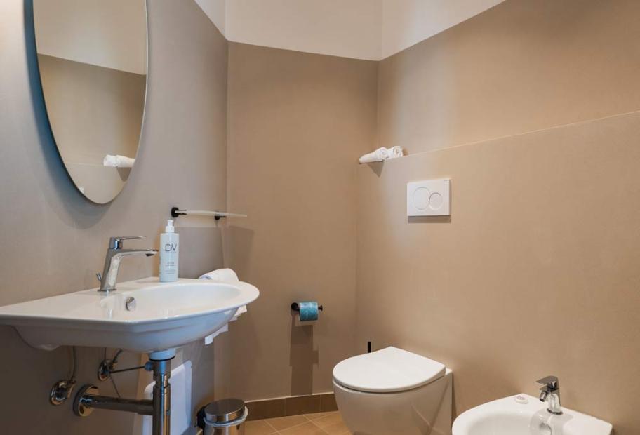 Modern, minimalist, cozy bathroom. Warm tones, oval mirror, elegant chrome details.