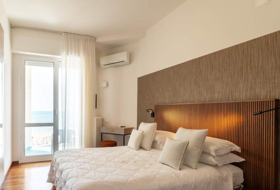 Modern room, cozy bed, bright sea view, relaxing and serene atmosphere.