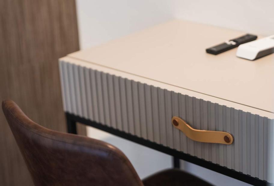 Modern desk with elegant drawer and leather chair, creating a cozy atmosphere.